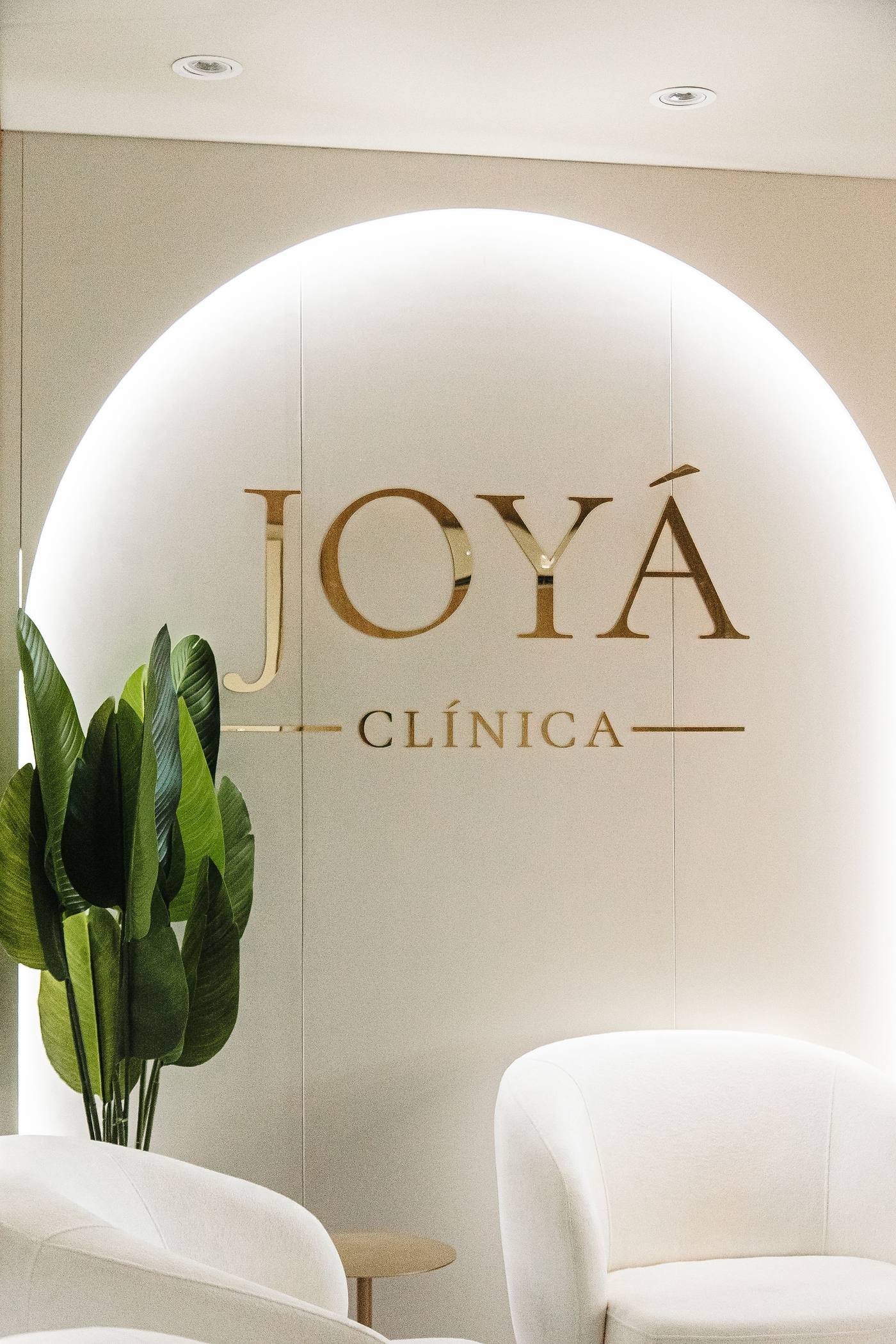 Arco iluminado com o logotipo dourado da Clínica Joyá